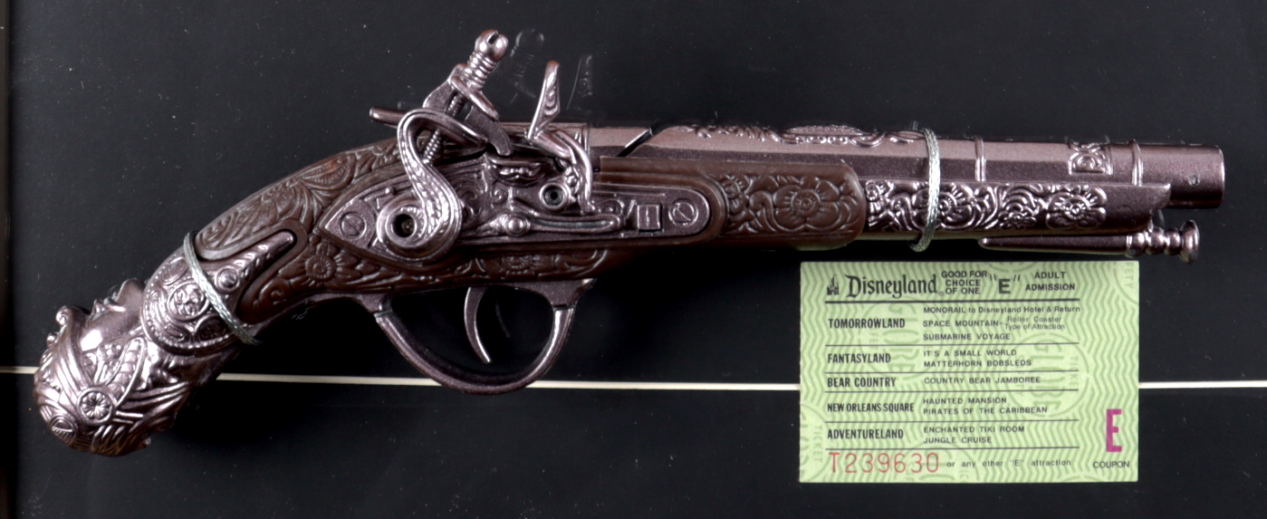 Disneyland "Pirates of the Caribbean" 15x26 Custom Framed Print with Pirates of the Caribbean Souvenir Gun & Vintage 'E' Pirates Ride Ticket at PristineAuction.com Disneyland "Pirates of the Caribbean" 15x26 Custom Framed Print with Pirates of the Caribbean Souvenir Gun & Vintage 'E' Pirates Ride Ticket at PristineAuction.com