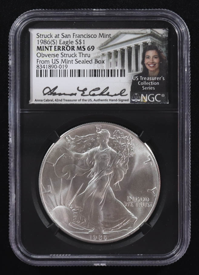 Mint Error 1986-(S) American Silver Eagle $1 Coin Struck at San Francisco Obverse Struck Thru - Anna Escobedo Cabral Signed Label (NGC MS69) at PristineAuction.com Mint Error 1986-(S) American Silver Eagle $1 Coin Struck at San Francisco Obverse Struck Thru - Anna Escobedo Cabral Signed Label (NGC MS69) at PristineAuction.com